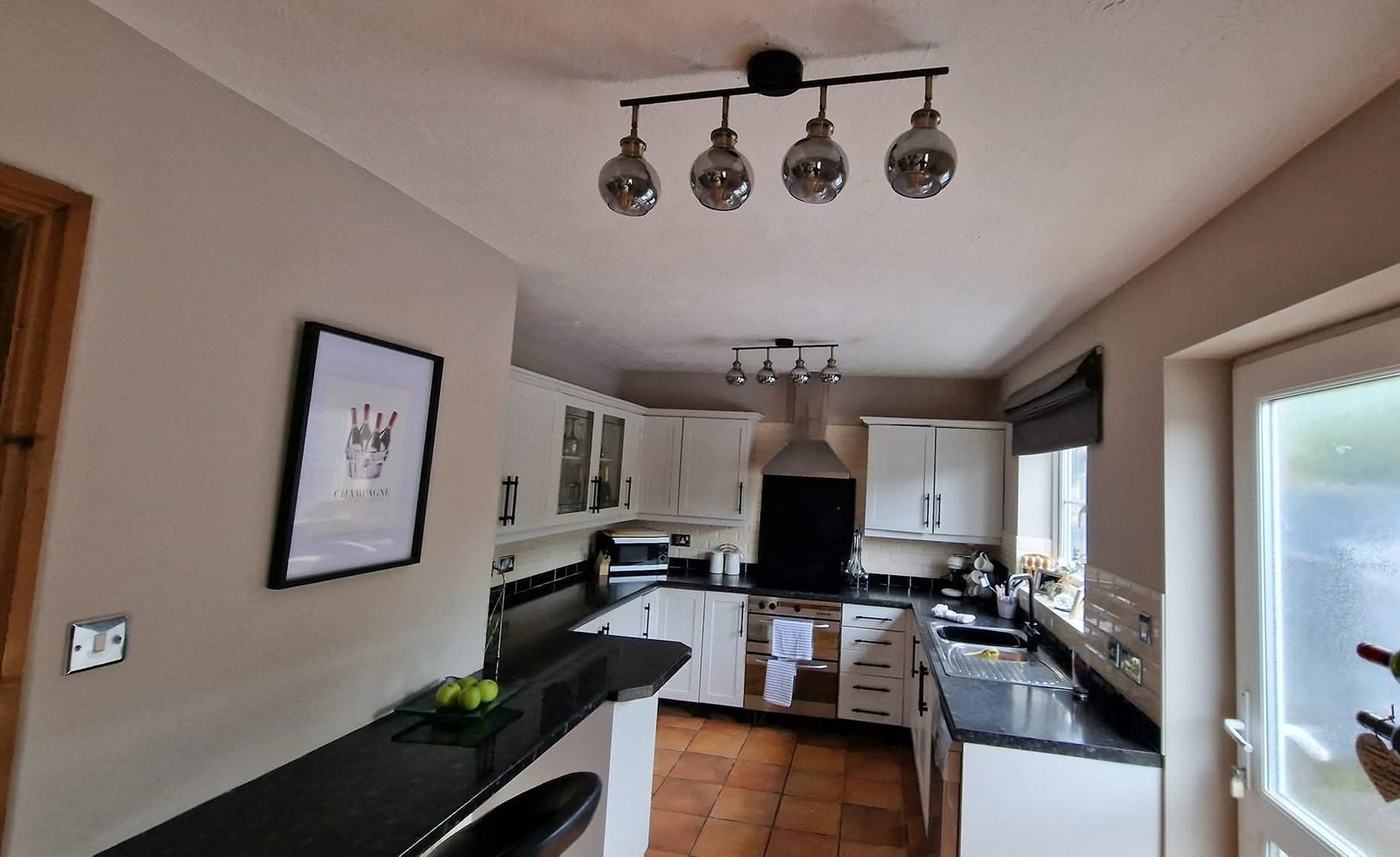Kitchen with new bar lighting over the island and spotlights beyond