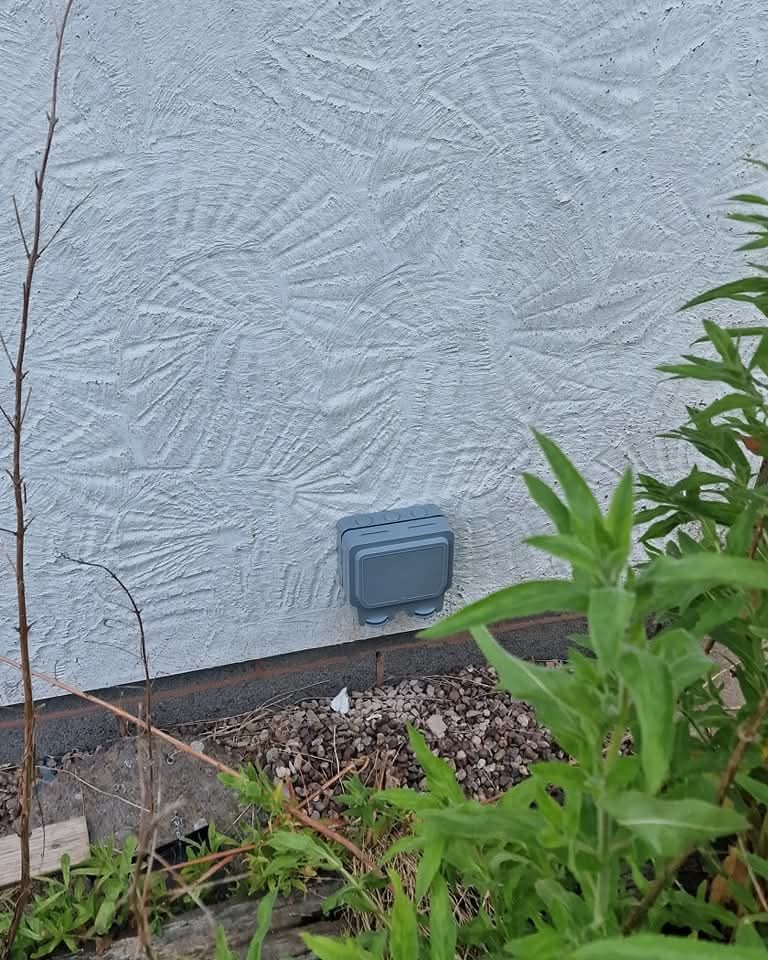 Weatherproof outdoor socket fitted to a rendered garden wall